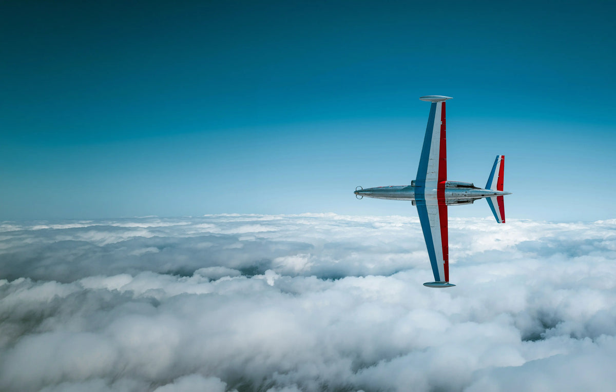 CM-170 Fouga Magister en vol sur la tranche au dessus des nuages, drapeau français sur les ailes