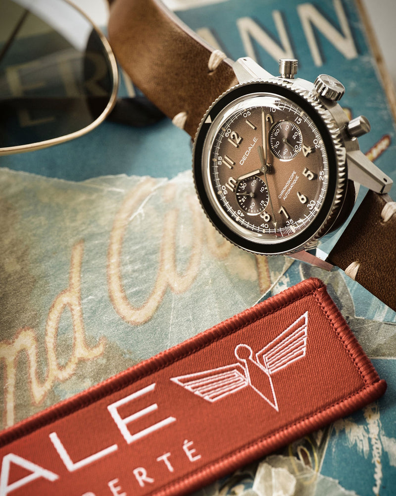 Montre d'aviateur DÉDALE WP-01 ALFA ZULU posée sur la première édition du livre 