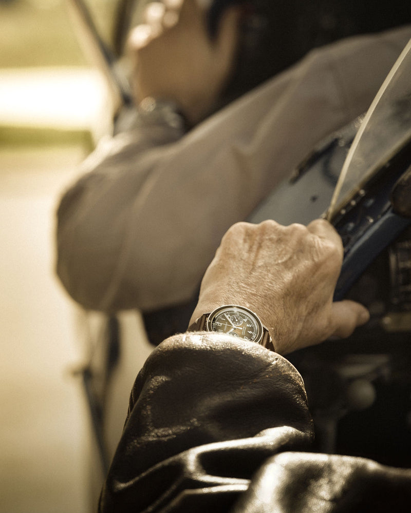 Pilotes d'avion dans le cockpit de leur aéronef de collection Bücker, portant chacun un chronographe d'aviateur DÉDALE Waypoint WP-01 ALFA ZULU.