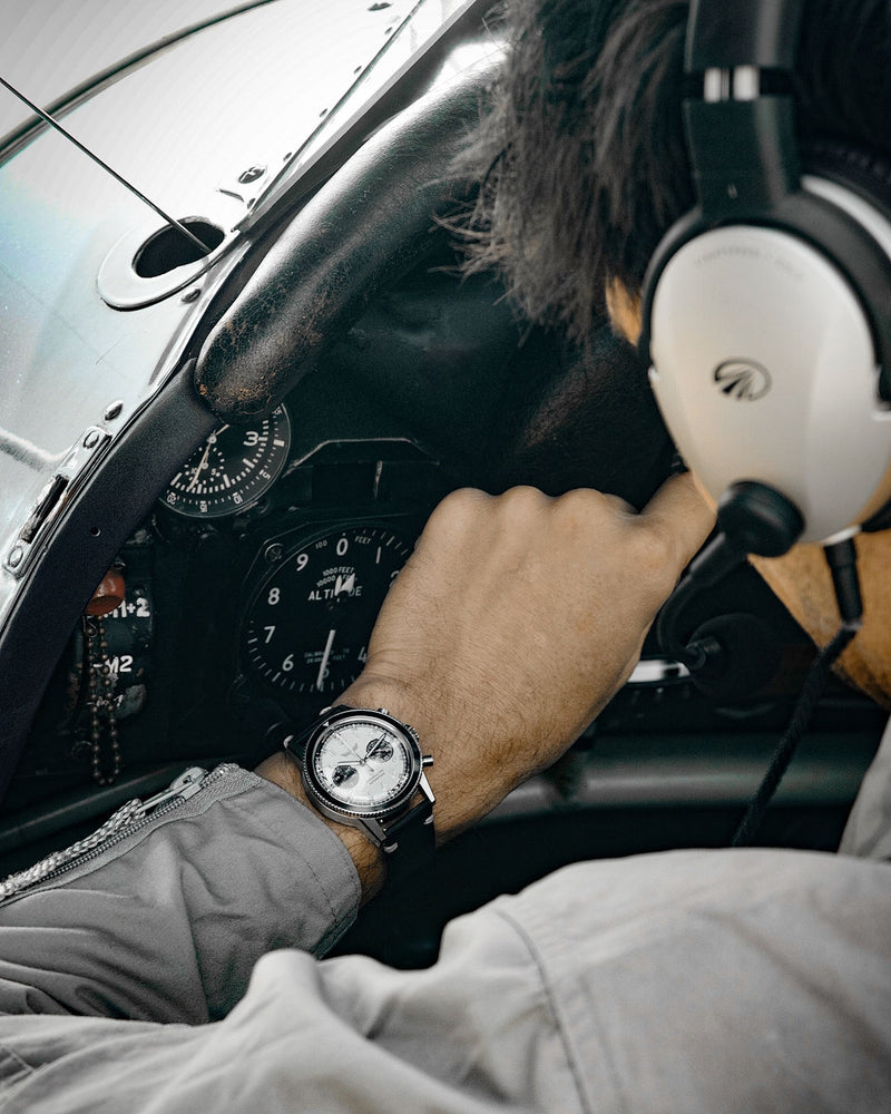 Pilote dans le cockpit de son avion vintage qui regarde son chronographe mécanique à remontage automatique DÉDALE Waypoint WP-01 PAPA