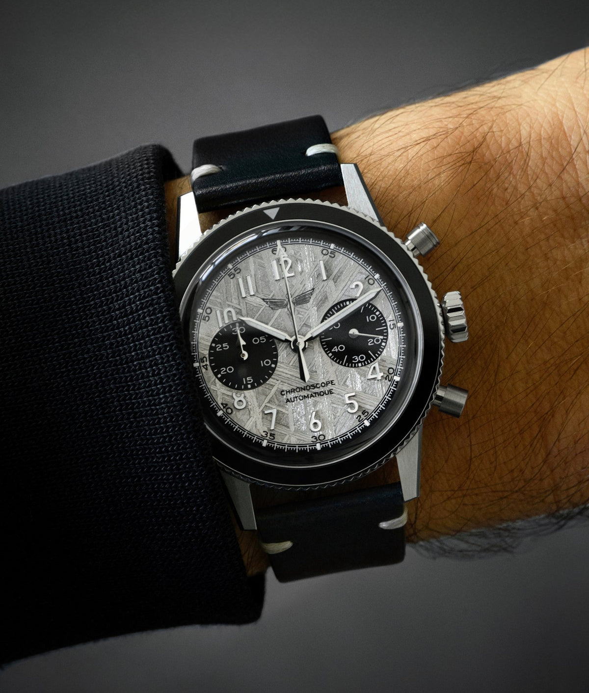 Chronograph watch with a meteorite dial, Widmanstätten patterns, worn on a men pilot's wrist